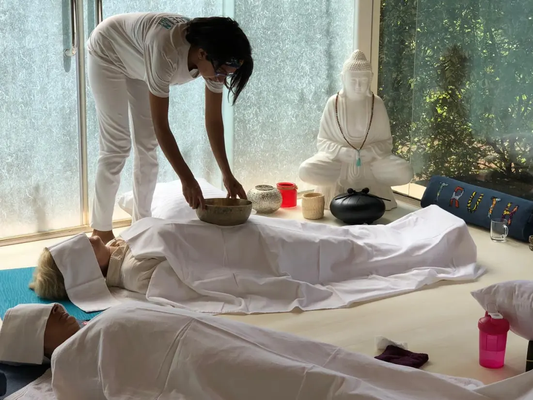 Nari placing a singing bowl on a participant during a group sound session