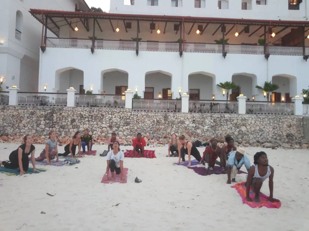 A diverse group practising together on the beach at dusk