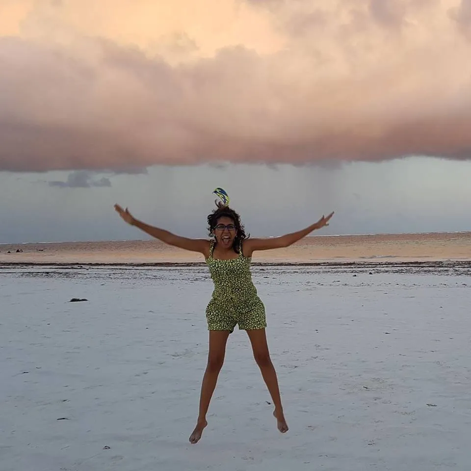 Narissa barefoot on the sand beneath a sunset sky